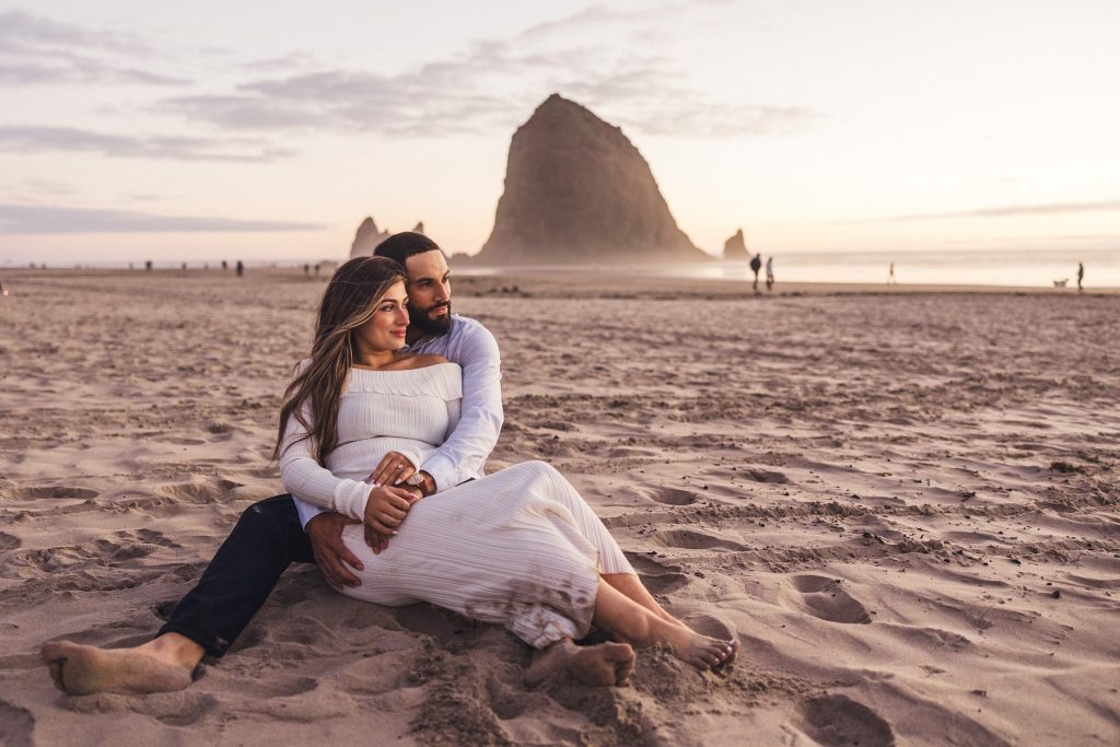 A couple relaxes in the sand for their Engagement Photographs in Cannon Beach